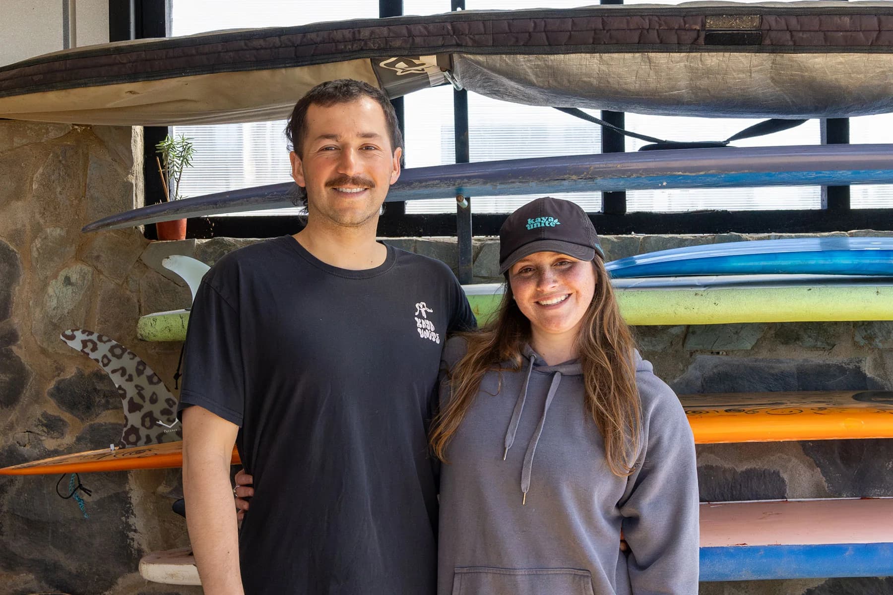 Pato y Meli, dueños de La Puntilla Surf, frente a las tablas de la escuela